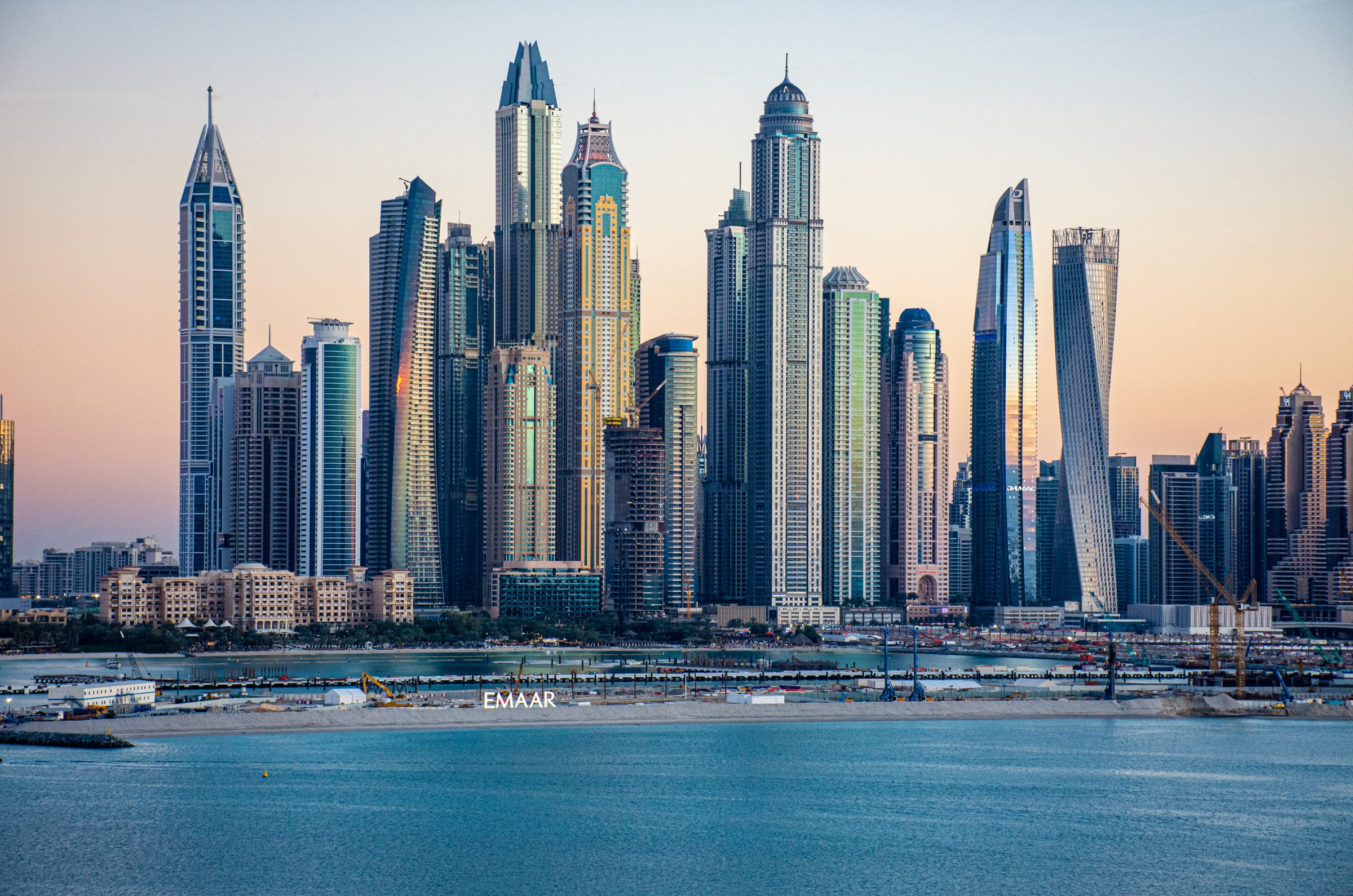 Dubai Marina au coucher du soleil, la ligne de tours résidentielles dominant l’eau, avec la plage et la marina en contrebas